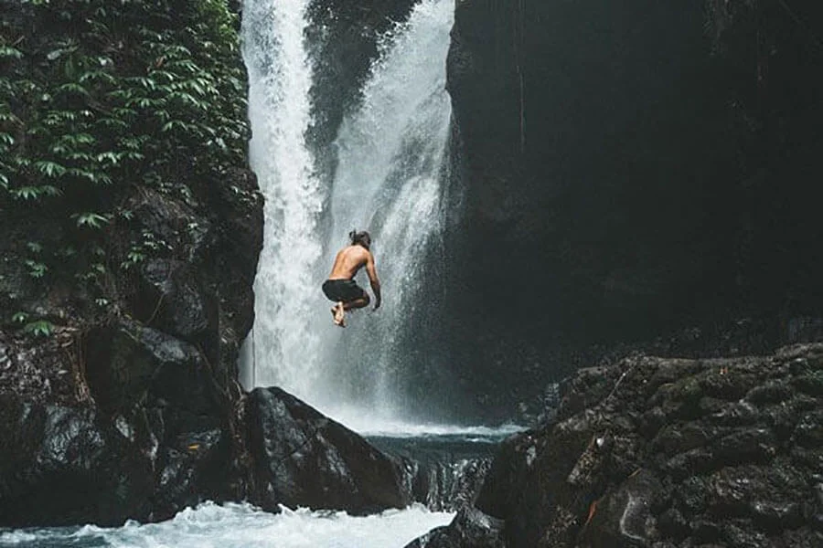 Guy jumps in Gitgit waterfall in Bali.