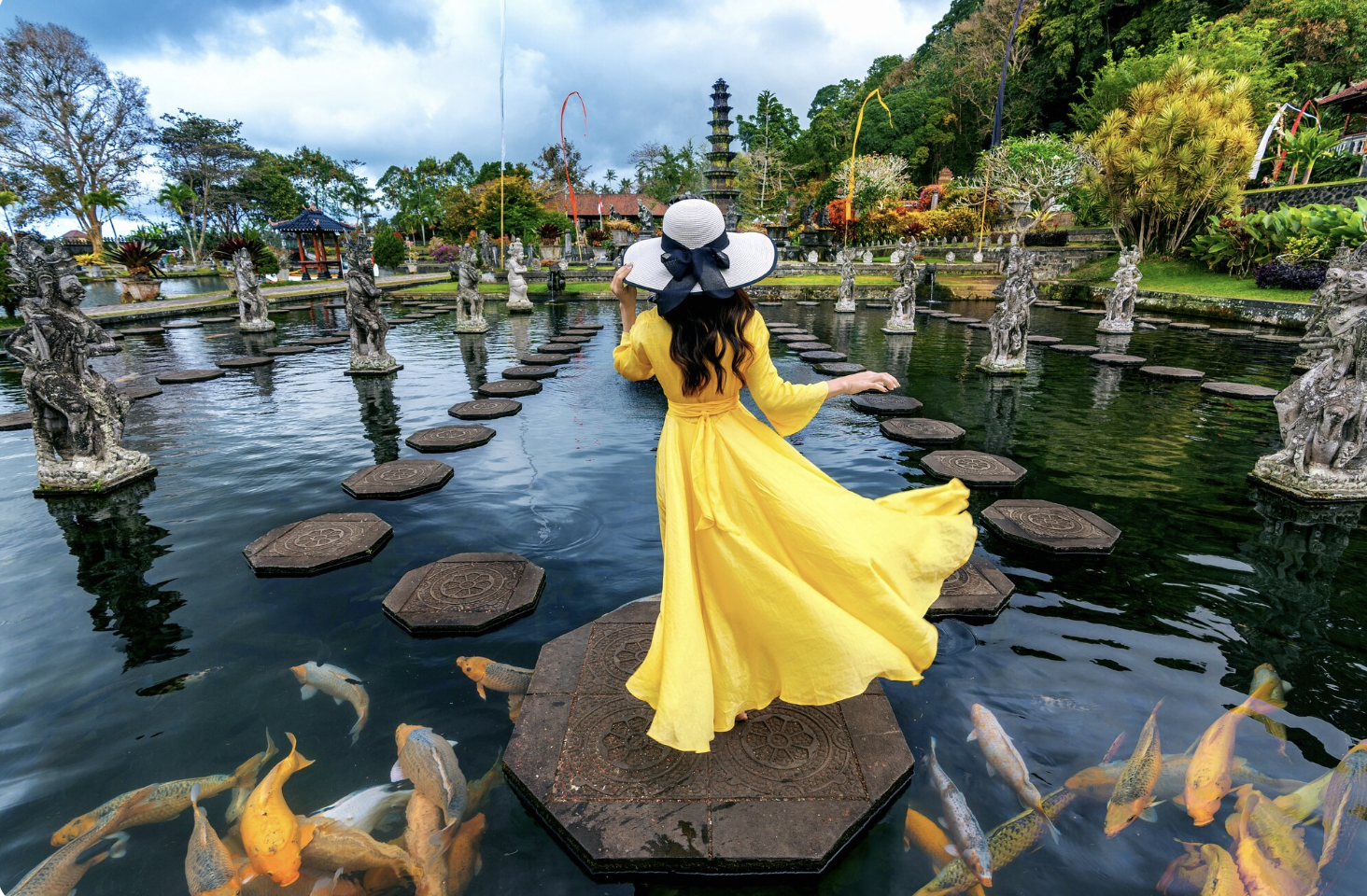 A woman posing in yellow dress in a fishpond in Bali