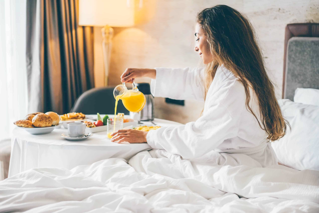 A woman with room service breakfast at a luxury hotel