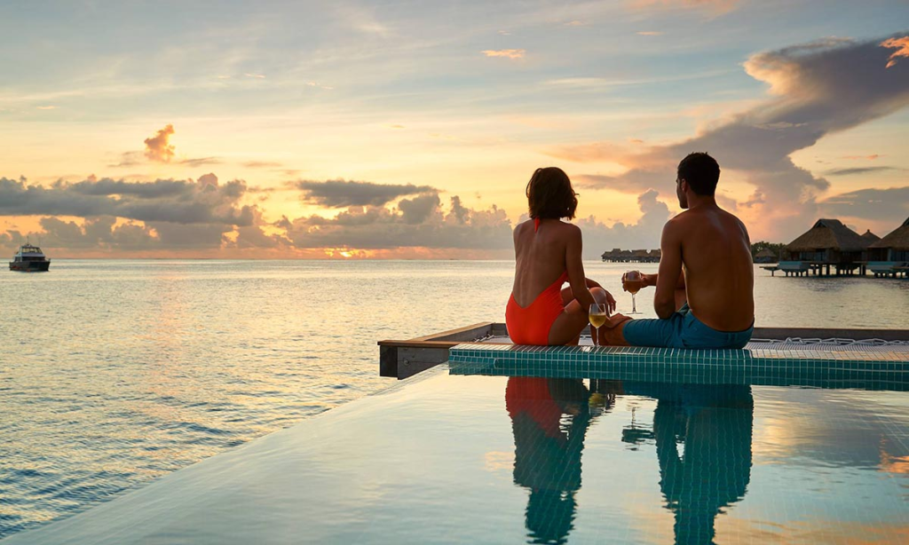 A couple holding glasses of wine and enjoying the sea view at a luxurious resort 