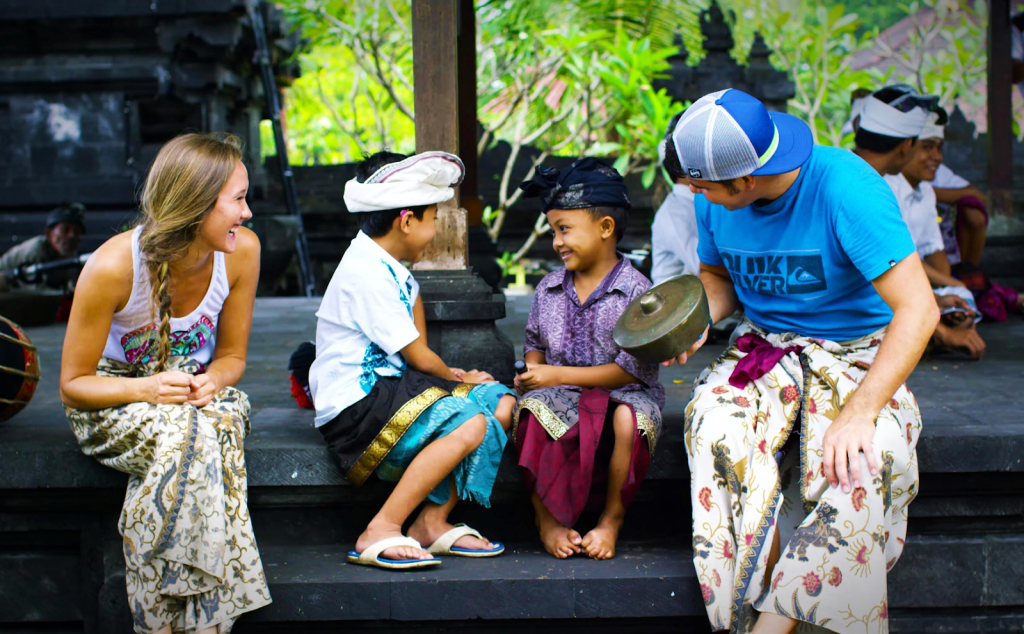 Two tourists sitting next to two local Balinese children