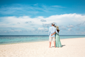 A couple standing on a pristine beach looking out to the ocean on their honeymoon