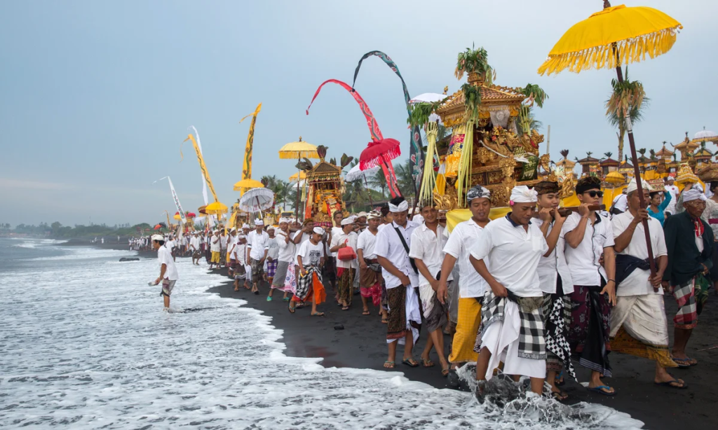 Balinese people walking along the beach in a ceremony for Nyepi