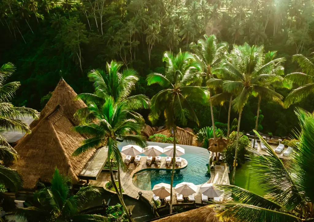 Aerial view of Viceroy Bali’s main infinity pool surrounded by lush tropical jungle, private cabanas, and luxury resort villas in the hidden Valley of the Kings in Ubud