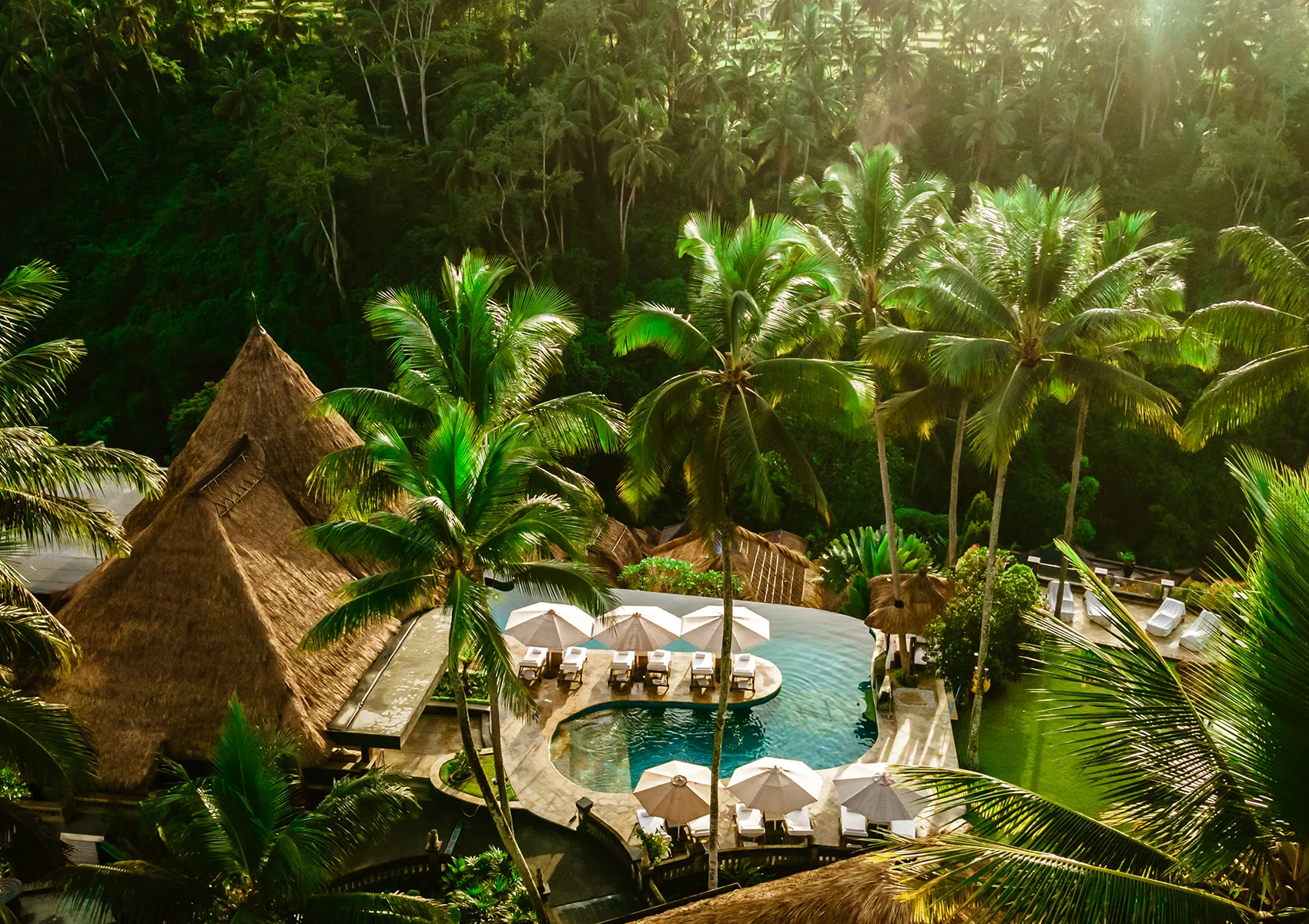 Aerial view of Viceroy Bali’s main infinity pool surrounded by lush tropical jungle, private cabanas, and luxury resort villas in the hidden Valley of the Kings in Ubud