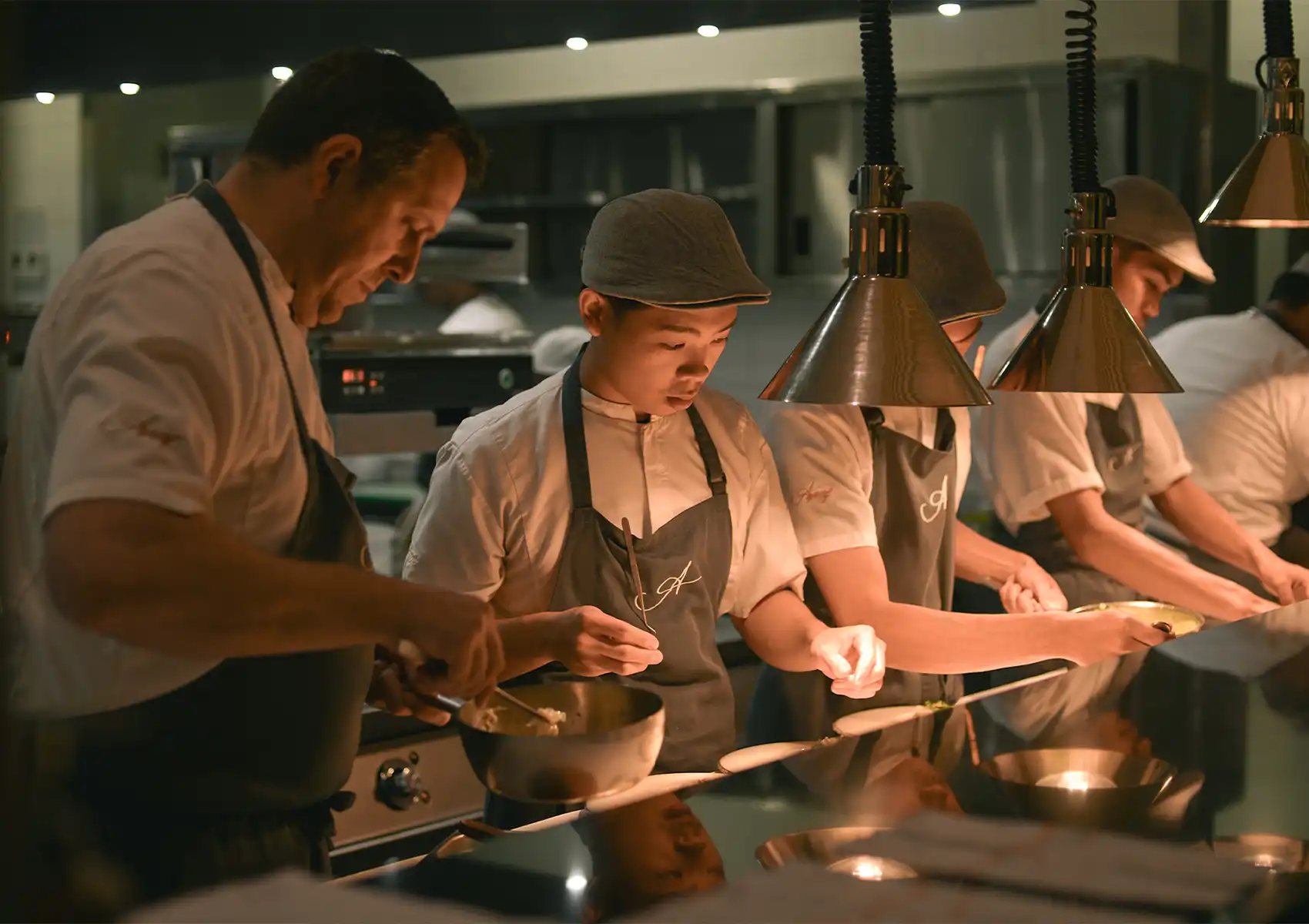 A team of professional chefs meticulously preparing and plating gourmet dishes in the warm, softly lit kitchen of a boutique hotel Ubud.