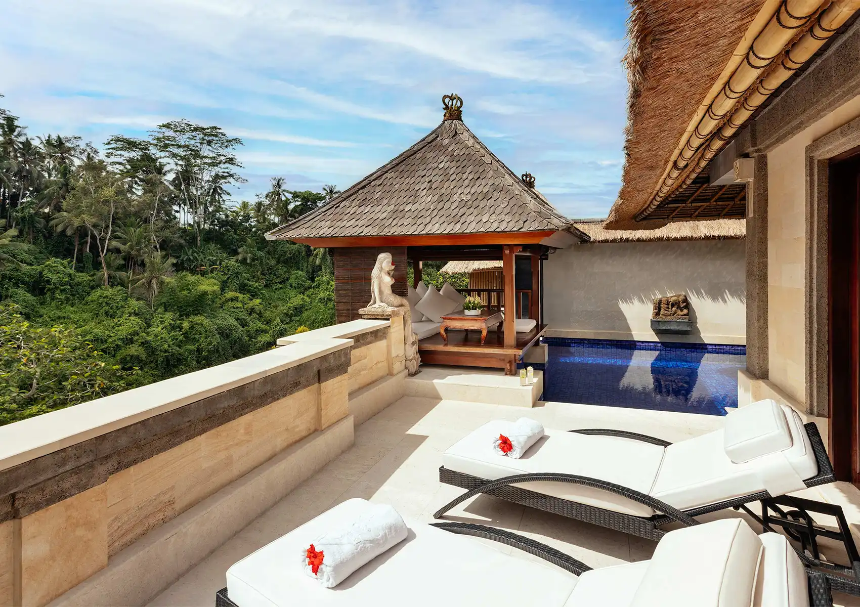 White sun loungers beside a private plunge pool and a traditional thatched-roof gazebo overlooking a dense jungle valley at a luxury retreat Ubud.
