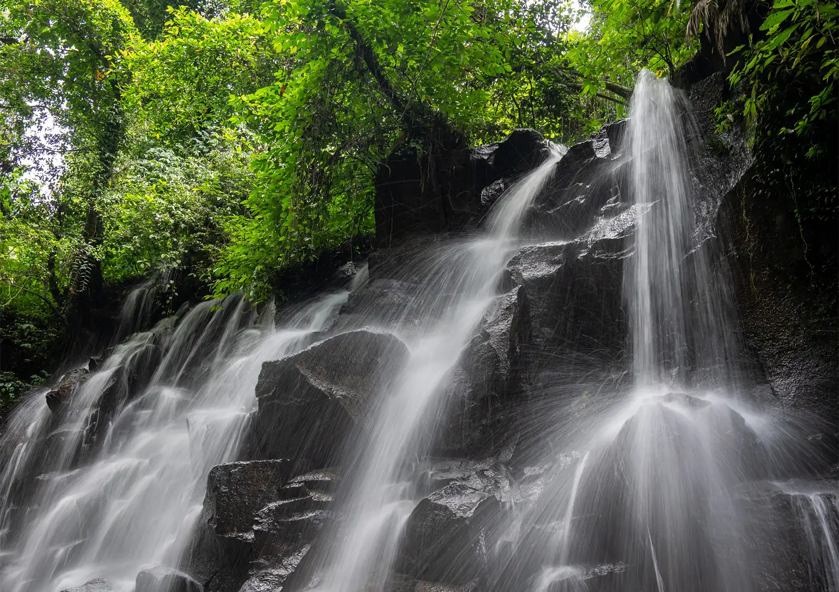 A scenic jungle waterfall cascading over dark rocks, a beautiful natural attraction to explore during a stay at a Private pool villa ubud
