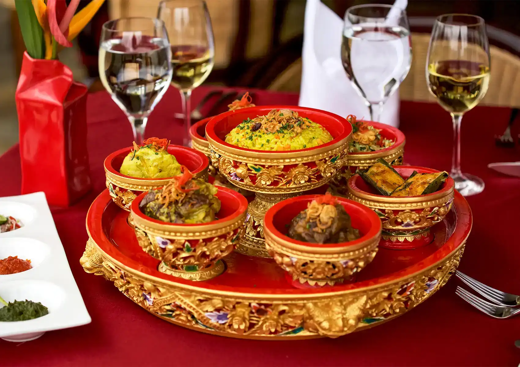 A traditional Balinese feast featuring yellow rice and flavorful side dishes served in ornate red and gold bowls for a holiday dinner at a boutique hotel in Ubud.