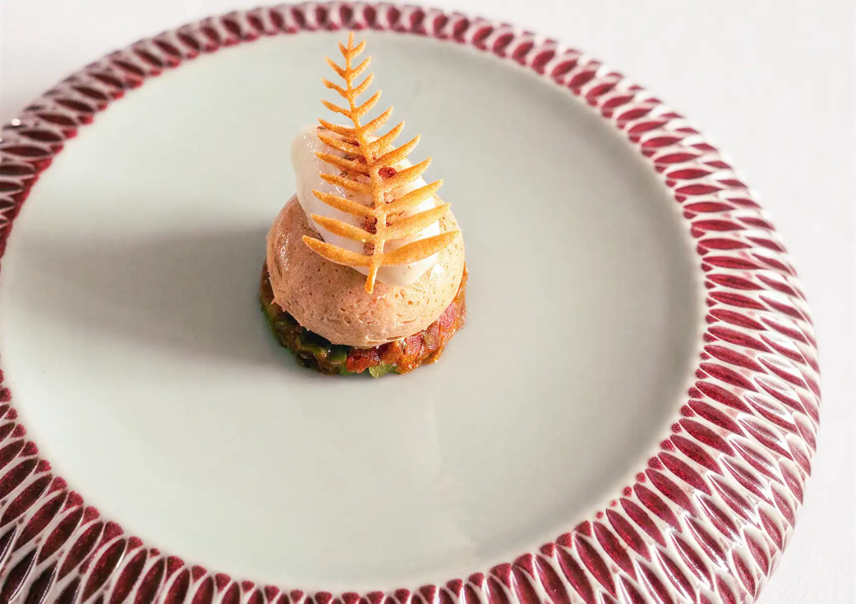 An elegant, gourmet plated dish topped with a delicate fern-shaped crisp served at a boutique retreat Ubud.
