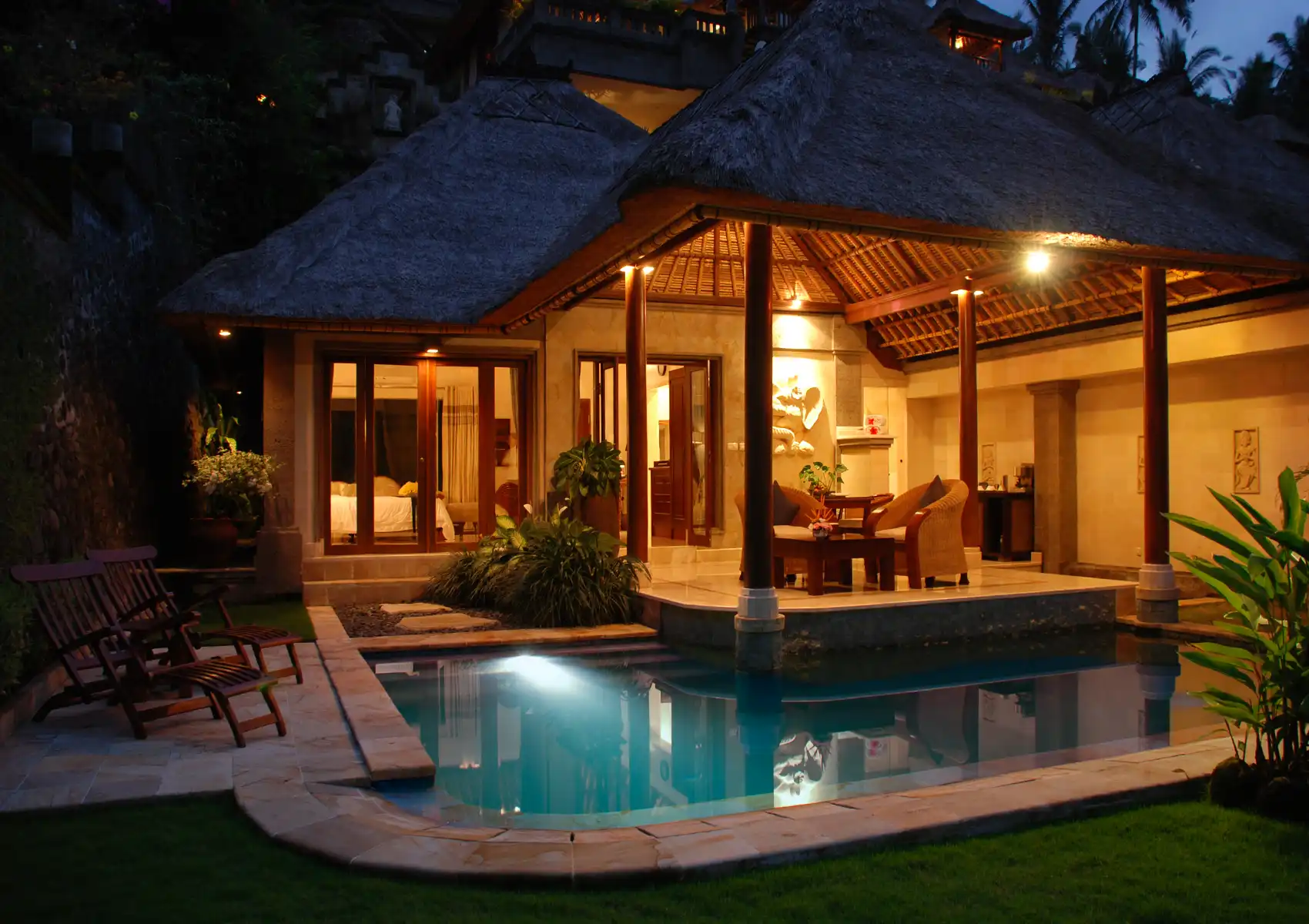 A private luxury villa featuring warm evening lighting, a covered outdoor patio with seating, and an illuminated plunge pool at a boutique hotel in Ubud.